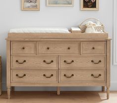 a baby's bed and dresser with pictures on the wall