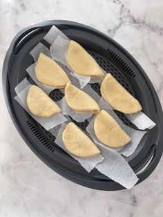 four uncooked pita breads sitting in an air fryer on a marble counter top