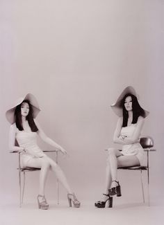 two women sitting in chairs with hats on their heads and one wearing high heeled shoes