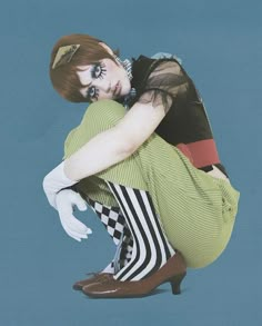 a woman sitting on the ground with her legs crossed, wearing tights and heels