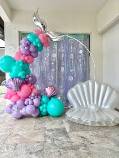 the balloon arch is made up of balloons and seashells for a mermaid themed birthday party