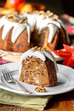 a bundt cake with white icing and nuts on top sitting on a plate