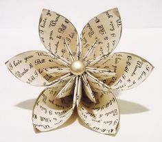 an origami flower made out of sheet music notes with a button in the center