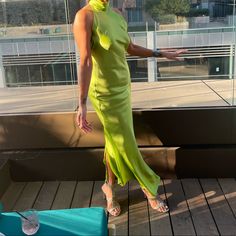 a woman in a green dress is standing on a wooden deck with her hand out to the side