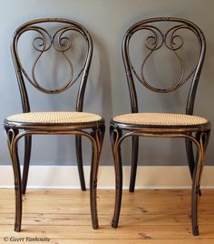 two chairs sitting side by side in front of a gray wall and wood flooring