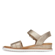 Bask in comfort and breezy style with the Skechers BOBS Desert Kiss sandals, the perfect metallic sandal for your adventures. Featuring a textured fabric upper, delicate woven jute trim at the heel, and a cushioned Memory Foam footbed, these sandals effortlessly blend comfort and chic for all-day wear. Vegan textured fabric upper Easy to wear slip-on styling with adjustable ankle strap Memory Foam cushioned footbed Espadrille style low wedge heel with woven jute trim Flexible sawtooth traction outsole Crafted with 100% vegan materials Spring Slip-on Footbed Sandals With Textured Sole, Summer Strappy Footbed Sandals With Cork-bed Midsoles, Beige Sandals With Cork-bed Midsoles, Beige Slip-on Sandals With Textured Sole, Gold Beach Sandals With Cork-bed Midsoles, Oxford Pumps, Skechers Bobs, Low Heel Wedges, Espadrilles Style