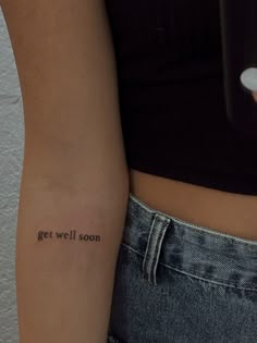 a woman with a tattoo on her arm that says get well soon in cursive writing