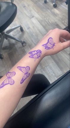 a woman's arm with purple butterflies tattooed on the side of her arm, in front of an office chair