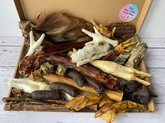 an open box filled with different types of meats and veggies on top of a white wooden table