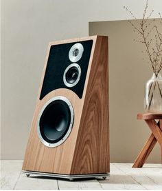 a wooden speaker sitting on top of a table next to a vase with flowers in it