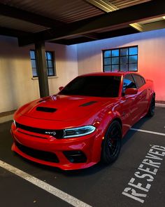 a red dodge charger parked in a parking lot next to a building with windows