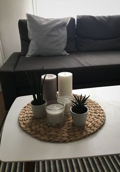 a living room with a couch, coffee table and two candles on top of it