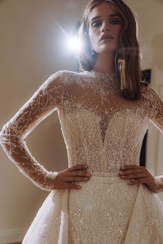 a woman wearing a wedding dress with long sleeves and beading on the neckline