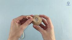 a person is holding a piece of yarn in one hand and the other with a button on it