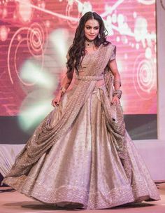 a woman in a silver and gold gown walking down the runway at a fashion show