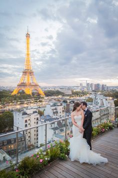 a bride and groom pose for a photo in front of the eiffel tower