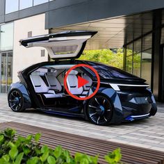 an electric car with its doors open sitting on the side of a road next to a building