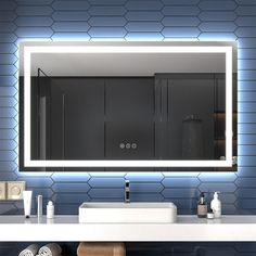 a modern bathroom with blue tiles and white counter top, lighted mirror above the sink