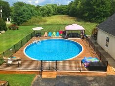 an above ground pool surrounded by lawn chairs and umbrellas in a backyard with a deck