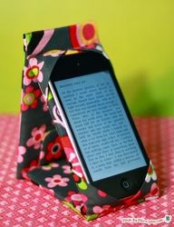 an electronic device sitting on top of a pink and green table cloth covered with flowers