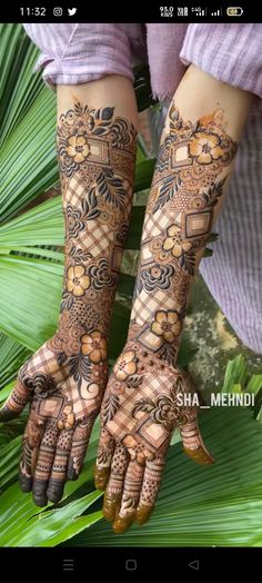 a woman's hands with henna tattoos on her arm and hand, in front of palm leaves