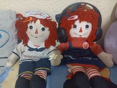 two ragged dolls sitting next to each other with headphones on and one wearing a sailor's outfit