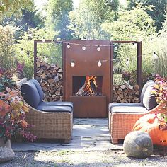 an outdoor fire place surrounded by wicker chairs and pumpkins