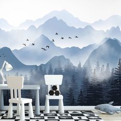 a living room with mountains and birds painted on the wall behind chairs, table and lamp