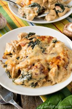 two white plates filled with chicken and spinach casserole on top of a table