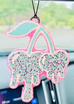 a pink and blue car decoration hanging from the dashboard