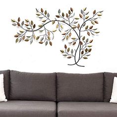 a couch sitting in front of a white wall with a metal tree design on it