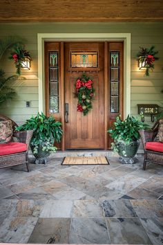 the front door is decorated with wreaths and potted plants