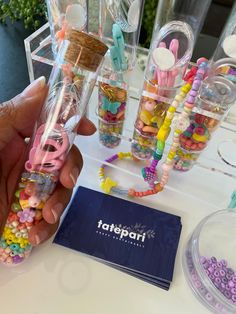 a person is holding up some candy in a glass tube with other candies around it