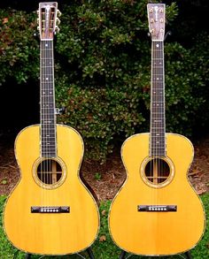 two guitars are sitting side by side in the grass, one is yellow and the other is black