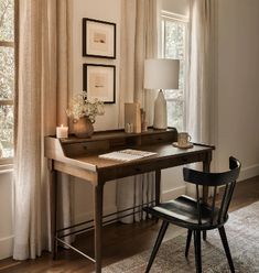 a desk with a lamp, chair and pictures on the wall