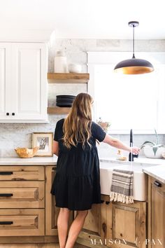 a woman standing at the sink in a kitchen