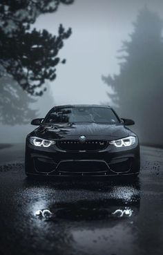 a black car parked in the rain on a road