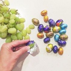 an advertisement for the easter egg hunt with grapes and chocolate eggs in it, as well as a woman's hand picking them