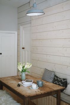 a wooden table topped with white flowers next to a wall covered in wood planks