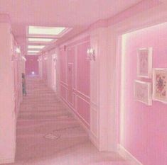 a hallway with pink walls and pictures on the wall