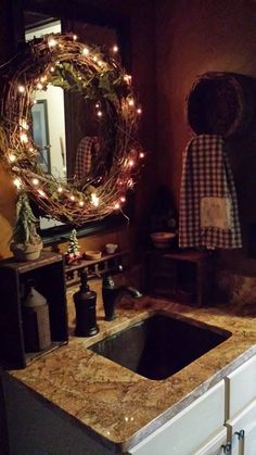 a bathroom sink under a mirror next to a counter with a wreath on top of it