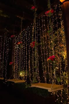 some lights hanging from the ceiling and flowers on display in front of them at night