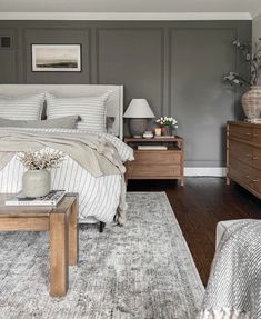 a bedroom with gray walls and white bedding, two nightstands and a large rug on the floor