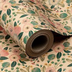 a roll of brown paper sitting on top of a flowery wallpaper covered in green and pink flowers