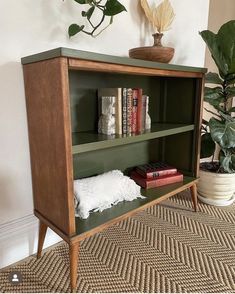 a book shelf with books and plants on top