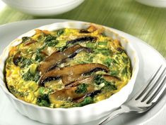 a white plate topped with an omelet covered in mushrooms and broccoli