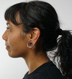 a close up of a person with ear piercings on their ears and wearing a black shirt