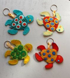 four different colored sea turtle key chains on a table