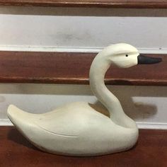 a white swan figurine sitting on top of a wooden floor next to some stairs