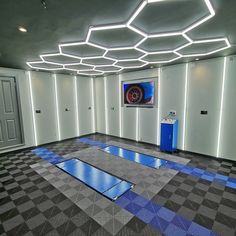 an empty room with blue and grey flooring in the center is lit by lights